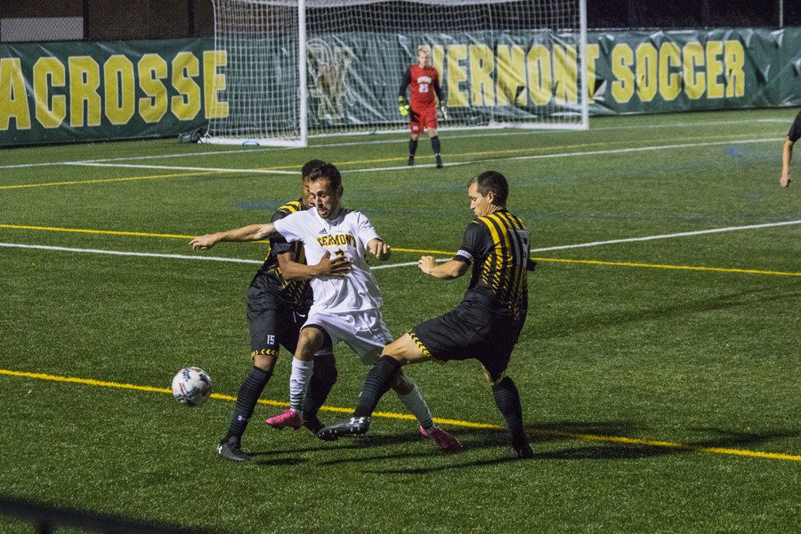 Junior forward Justin Freitas dribbles between two UMBC players Oct. 21. Freitas scored twice in the game, carrying the Catamounts past the Retrievers 3-1.