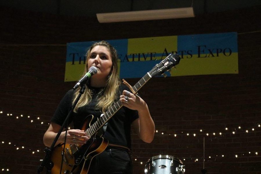 Sophomore Emily McDonnell strums a guitar and sings at the The Creative Arts Expo on Trinity campus Mar. 29. Over 200 people attended the expo and 50 participated in the open mic.
