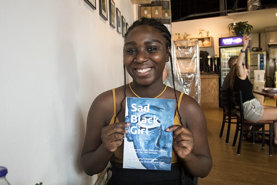 Junior Harmony Edosomwan poses with her new book, Aug. 22. The book, titled “Sad Black Girl,” is an interactive poetry book filled with Edosomwan’s words, places to write or draw the reader’s own feelings and art made by friends and strangers.