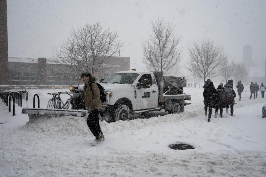 A UVM Physical Plant employee plows snow with a pickup truck as students navigate around him, Feb. 8. UVM’s snow removal equipment is housed under the old bleachers at Centennial Field.
