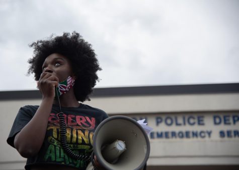Protest organizer Harmony Edosomwan stands on top of a blue pick-up truck speaking to the crowd with a megaphone at the May 30 protest.