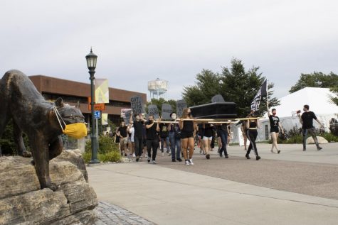 Students march from the Davis Center to Waterman Green Sept. 3, carrying a large black coffin and wielding tombstone-shaped signs representing the death of Black Americans and potential death of UVM's reopening plan.