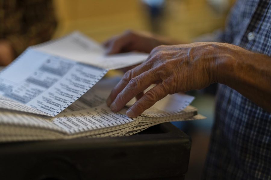 The ballot counter leafs through the ballots, handing his partner one at a time Oct. 29. He said typically he would be licking his fingers to get through the ballots more quickly, but COVID has put a halt to that.