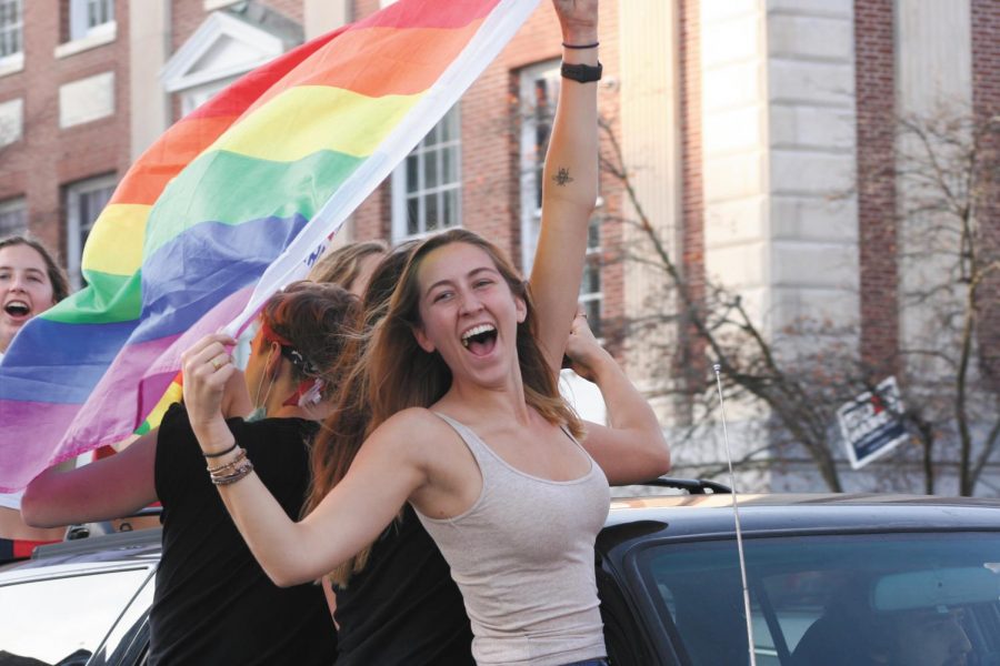 A girl rides in the car with her friends down Main St while waiving the pride flag Nov. 7.