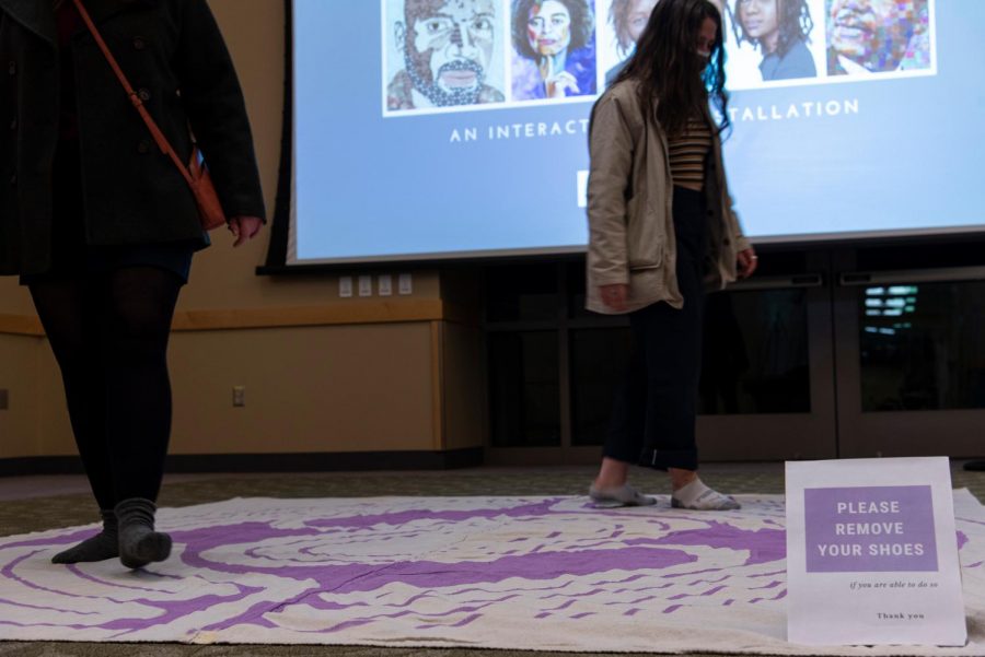 Two students participate in the Putting Feet into Faith interactive art installation Feb. 24.