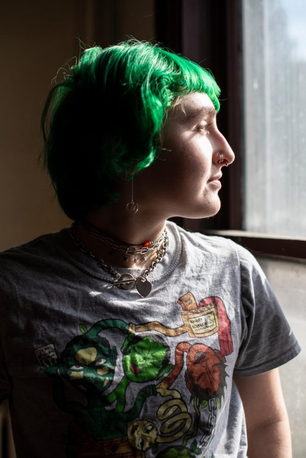 Katz stares outside their window onto Colchester street March 3. Katz is wearing an assortment of chokers and a T-shirt designed by a non-binary California artist.