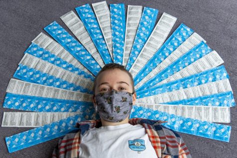 Freshman Elene Karlberg, known as UVM Condom Kid, poses surrounded by over 100 Trojan condoms March 31.