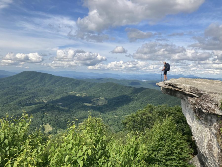 Palladino standing on the edge of a small cliff overlooking a mountain range.