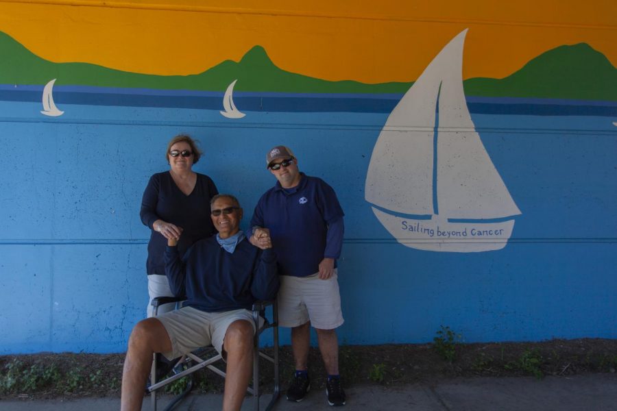 Cancer survivor Steve Milizia, his wife and son pose in front of a mural that memorializes his experiences with Sail Beyond Cancer.