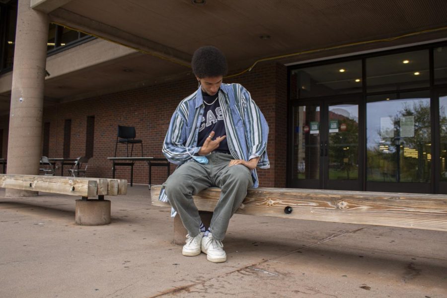 Junior Miles McCallum poses outside the Howe Library wearing clothes that resemble a retro-adjacent style. 
