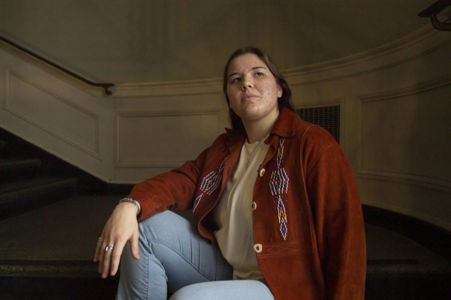 Junior Maddie Henson sits in the Waterman Building wearing a jacket with deer bone buttons passed down through her family Nov. 13. Henson’s rings have also been passed down to her, they represent the wings of life, mother earth and father sky, she said.