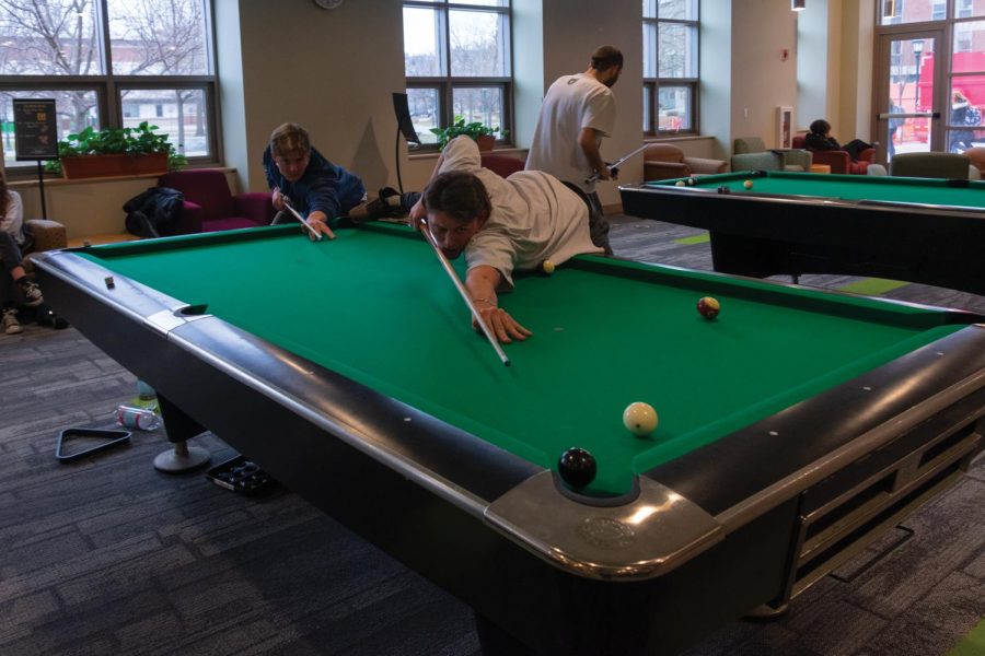 A student lines up a shot of an 8-ball game in the Davis Center lounge.
