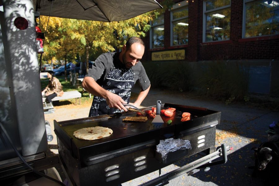 Daryoush Khamnei prepares food at his food cart, Micro Mobile Kitchen, at the Burlington Farmers Market Oct. 22. His business supports Iranian culture in Vermont.