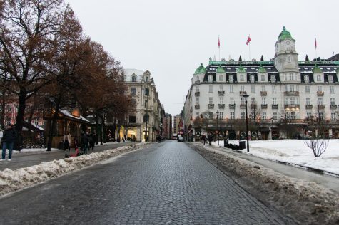A street in Oslo flanked by a Christmas market (left) and a governmental parliament building (right).