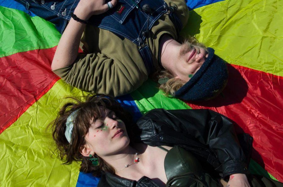Sophomores Evan Dodge and Emma Luikart laying on a colorful blanket on the Redstone green.