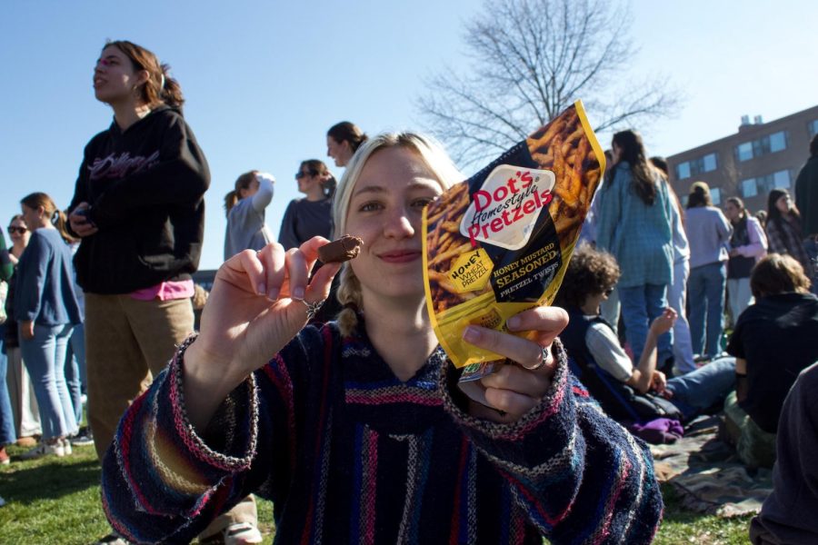 A student enjoys pretzels and a Milky Way on the Redstone green.