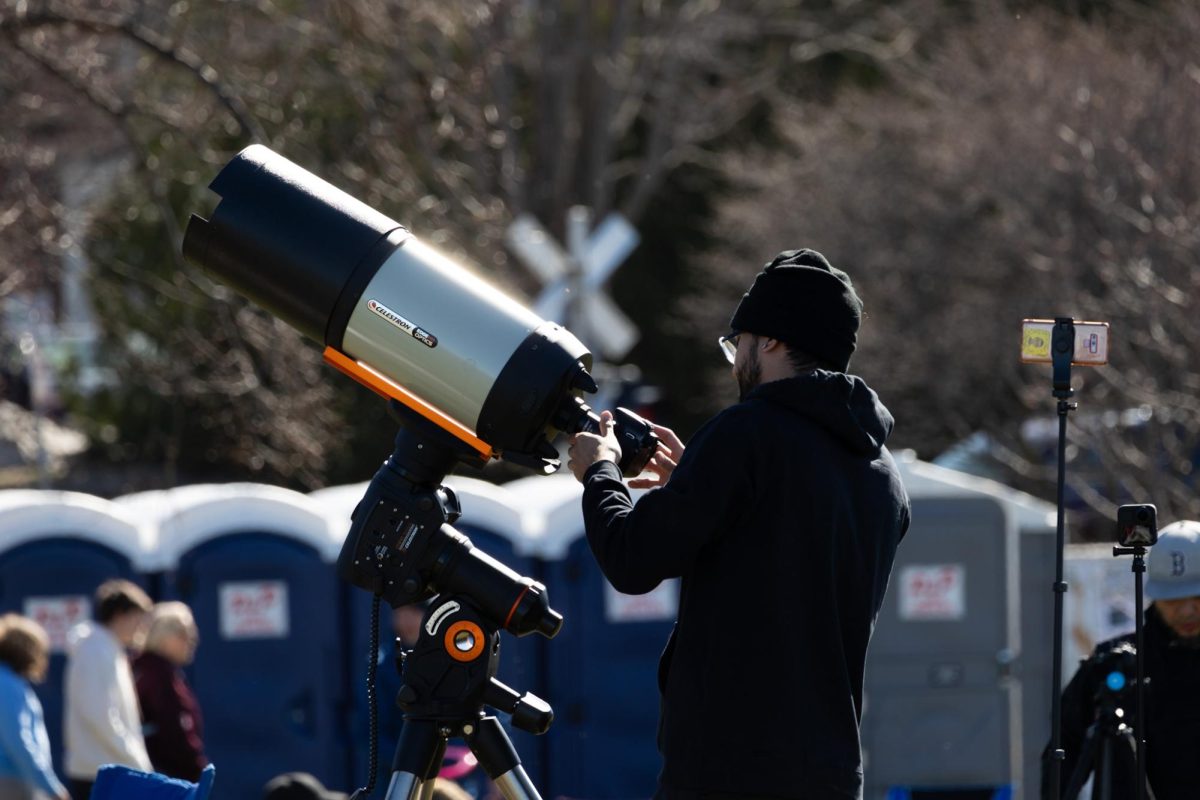 A photographer attaches his camera to a large telescope in Battery Park.