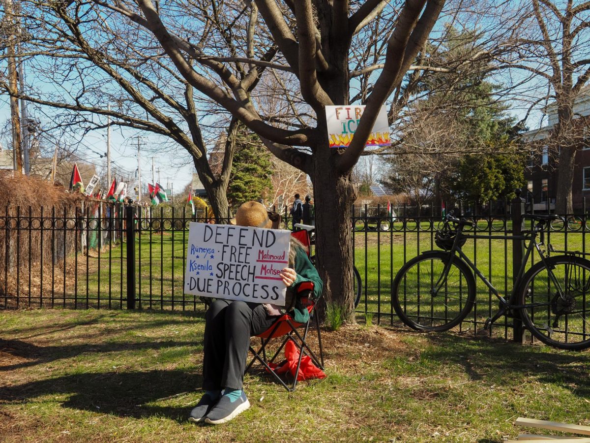 Protester sits in a lawn chair holding a sign.